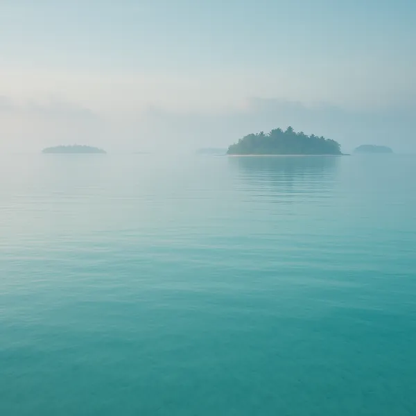 This online jigsaw puzzle features a tranquil seascape with small tropical islands and soft morning mist, designed for soothing browser play.