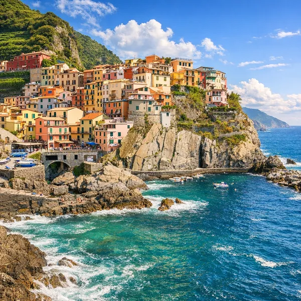 Enjoy an online jigsaw puzzle designed for browser play, featuring a sunlit coastal village perched on rugged cliffs above a sparkling blue sea.